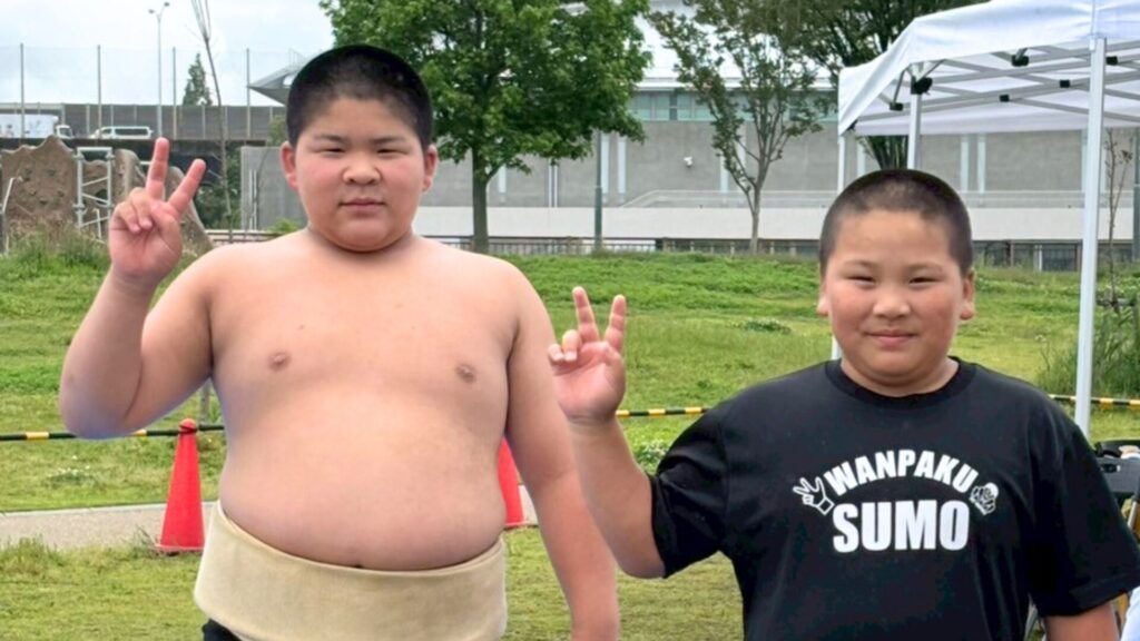 相撲体験ブースにて、まわしを締めて笑顔でポーズをとる子どもたちの様子
